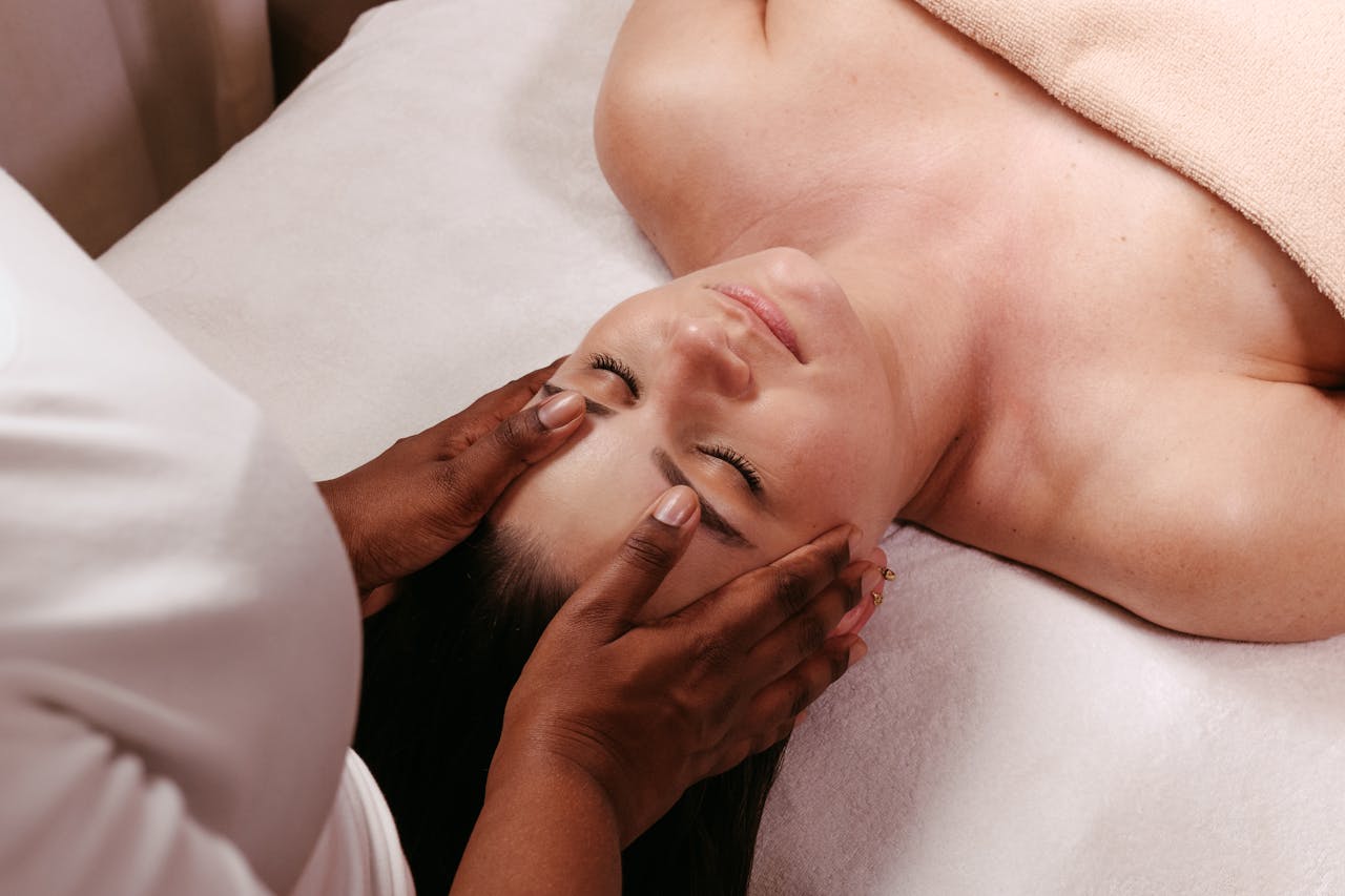 A woman enjoys a serene head massage in a spa setting, promoting wellness.