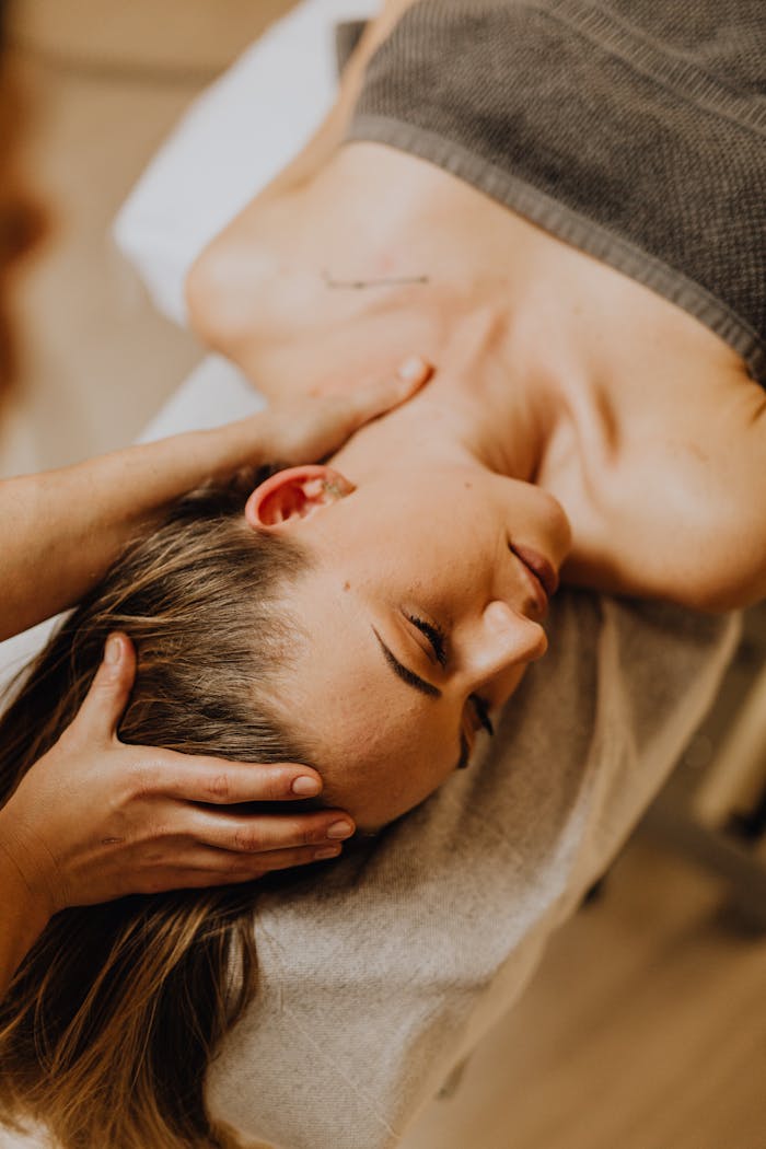 A woman receiving a head and neck massage in a serene spa setting, promoting relaxation and wellness.