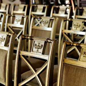 A row of ornate gold chairs arranged for a formal event or ceremony indoors.